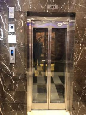 Glass elevator door with hairline finish